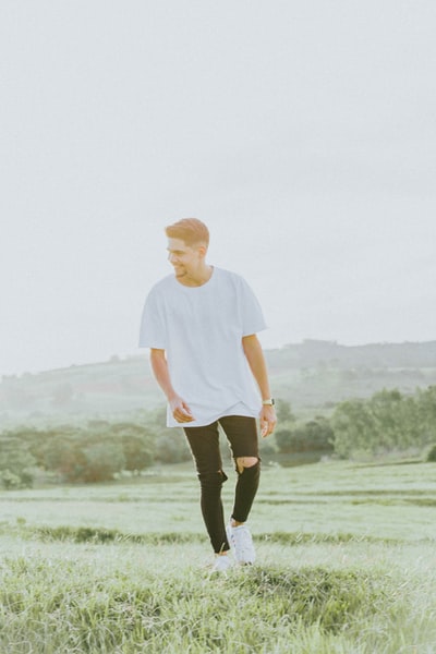 man in white crew neck t-shirt and black shorts standing on green grass field during